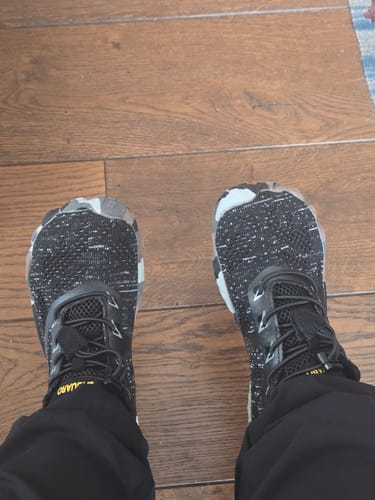 Customer's top-down view of their black, speckled Smart II Barefoot Shoes on a wood floor.