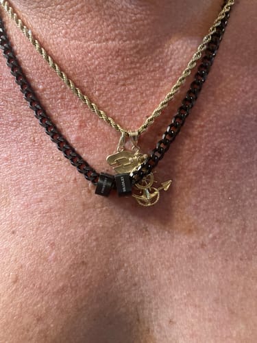 Close-up of a customer wearing the black Legacy necklace with personalized beads, layered with another chain.