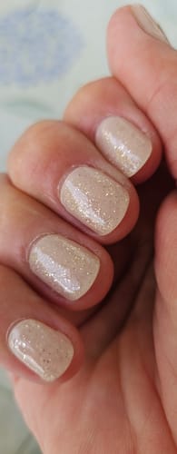 Kundin zeigt ihre Nägel mit dem UV Top Coat Gold Glitter Bold.
