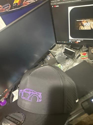 Customer's black 80Eighty DCG88 Hat with a purple embroidered car outline sitting on a desk.