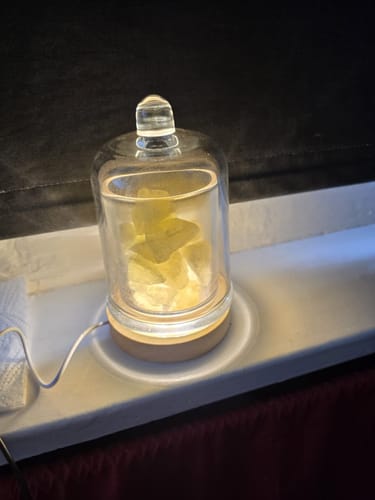 Die Kristall-Diffusor Lampe eines Kunden steht beleuchtet auf einer Fensterbank und bringt die Kristalle zum Leuchten.