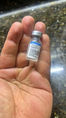 Cliente mostrando un pequeño vial del suplemento Post NovarX 10,000 en la palma de su mano.