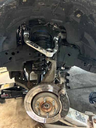 Customer's silver Forged Aluminum Upper Control Arm installed inside the wheel well of a truck.
