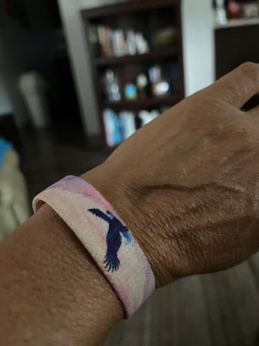 A customer's wrist wearing the On Wings Like Eagles bracelet, showing the blue eagle graphic on the band.