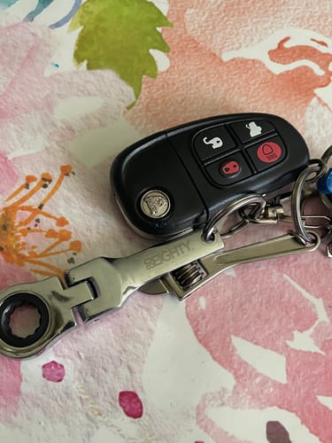 Customer's shiny 10mm Wrench Keychain attached to a car key fob on a floral surface.