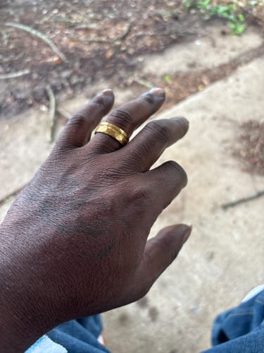 Close-up of a customer wearing the faceted gold Dominus ring on their finger.