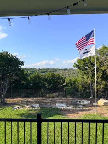Customer's heavy duty American Flag waving on a flagpole in a scenic backyard.