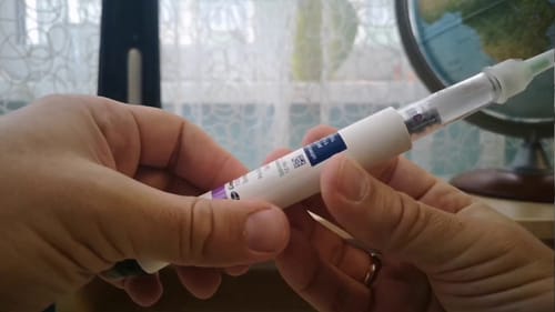 A customer holding the Genotropin GoQuick Pen in their hands, with a globe visible in the background.