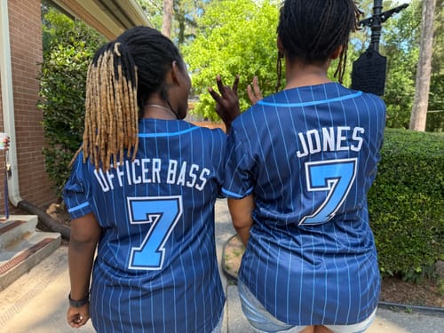 Customers showing the back of their custom navy pinstriped baseball jerseys with their names and the number 7.