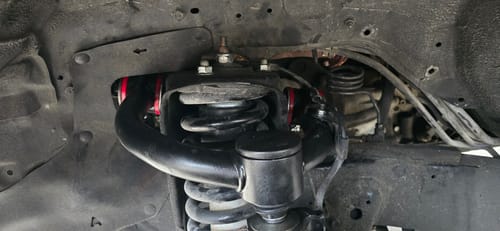 Customer's new black Lift Upper Control Arms with red bushings installed in the wheel well of their Toyota.