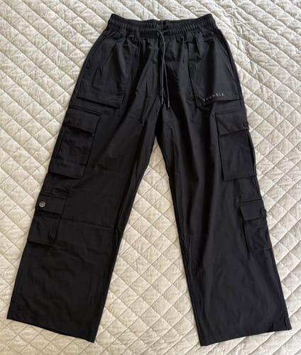 Customer's black Baggy Gym Cargos laid flat on a quilted surface, showing the relaxed fit and multiple pockets.