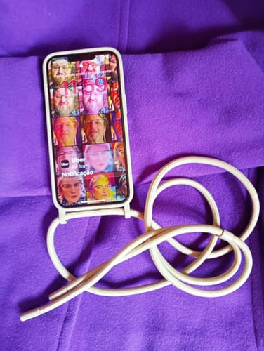 Cliente mostrando a Case Areia com alça em um iPhone sobre um fundo roxo.