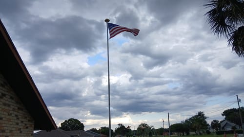 Reviewer's American flag flying from a flagpole against a cloudy, gray sky.