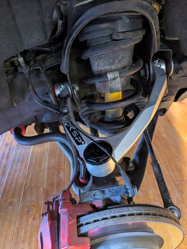 Customer's photo of a newly installed, shiny Aluminum Forged Control Arm on a vehicle's suspension system.