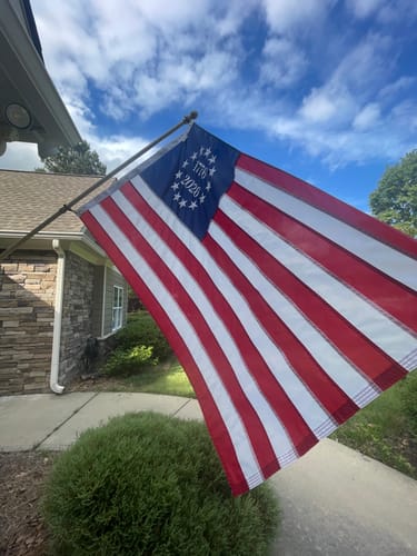 Customer's 1776 to 2026 Betsy Ross Flag with embroidered stars flying on a pole outside a house.