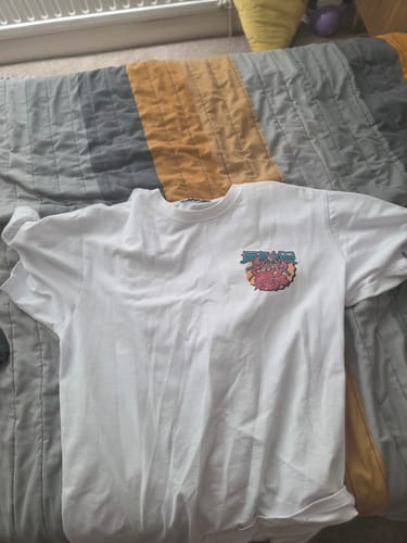 Customer's white Mount Fuji T-Shirt laid flat on a bed, showing the small chest graphic.