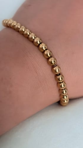 Close-up of a reviewer wearing a delicate gold bead bracelet on their wrist.