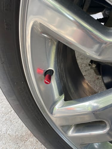 Customer's red 80Eighty valve stem cap installed on a shiny chrome wheel.