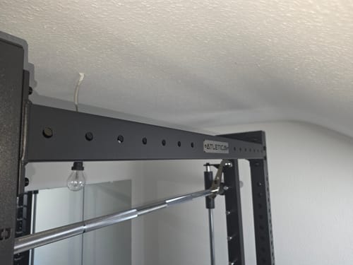 Rezensent zeigt die installierte R7 Crossbar mit dem hochwertig verarbeiteten Atletica-Logo in Nahaufnahme.