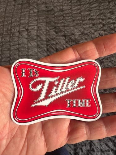 Customer's hand holding a red, custom-shaped vinyl sticker with a white border that reads 'It's Tiller TIME'.