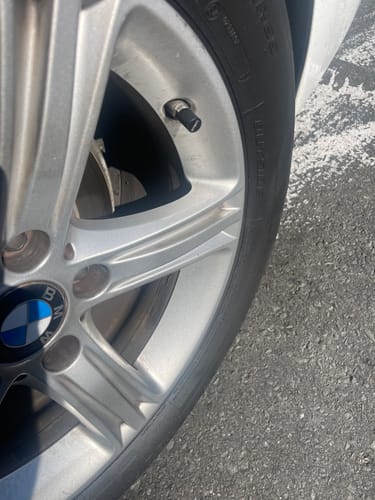 Customer's close-up of a black 80Eighty® Valve Stem Cap installed on a silver car wheel.