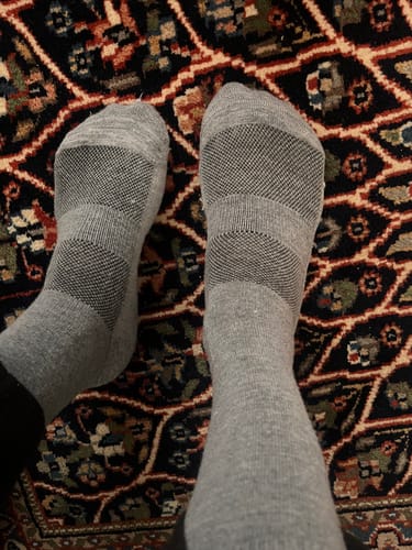 Customer wearing the grey Crew Socks, showing the textured bands across the top of the feet.