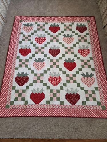 Customer's finished quilt with a strawberry pattern and a red gingham border.