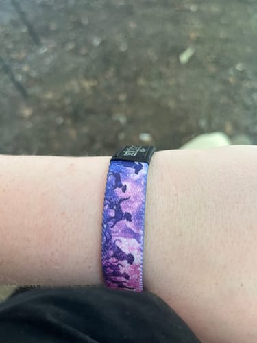 A customer's wrist wearing the 'Until We Meet Again' Dog Bracelet, which has a purple and pink design with dark dog silhouettes.
