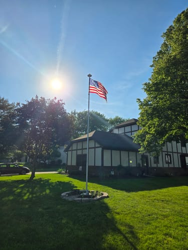 Reviewer's photo of an American flag waving on a flagpole in a sunny front yard.