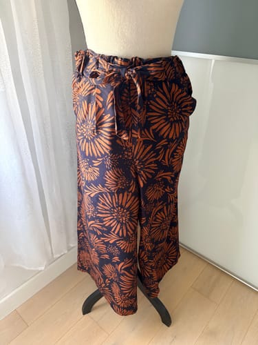 Cliente présentant un pantalon confectionné avec le coupon de viscose imprimé bleu marine à motif orange.