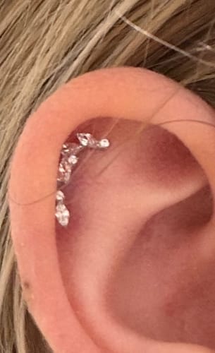 Close-up of a customer's ear wearing the sparkling Climbing ivy flatback silver earring in a helix piercing.