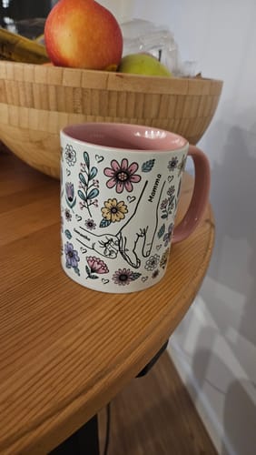 Kundens Kärleksmugg med rosa insida, med ett blommigt motiv av händer och texten 'Mamma'.