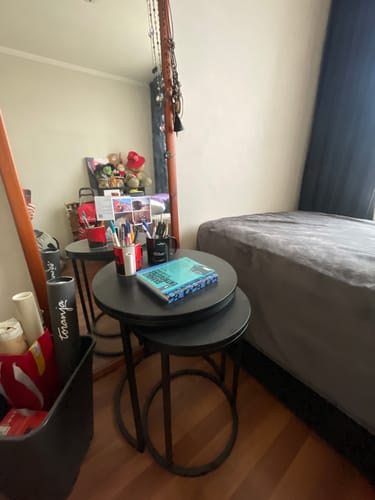 Un cliente muestra el conjunto de mesa lateral nido circular BLACK que utiliza como mesa de noche en su dormitorio.