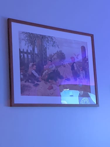 Customer's framed 'Mayhem' art print hanging on a wall under blue light.