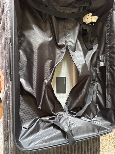 Reviewer shows the SPOTMINDERS. Tracking Card placed under the lining of an open suitcase.