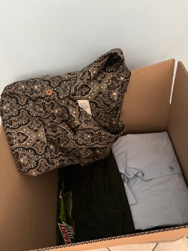 Cliente mostra la scatola per reselling aperta con all'interno dei capi di abbigliamento piegati.