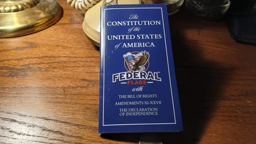 Customer's United States Pocket Constitution, a small blue book, resting on a wooden table.