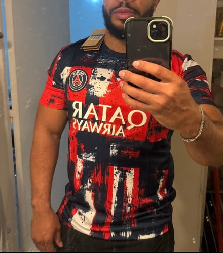 Un client prend un selfie dans un miroir en portant le Maillot 25/26 PSG red Spécial à motif graphique.