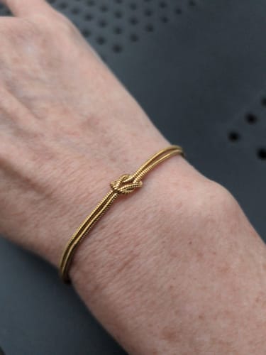 Reviewer's slender wrist wearing the gold-colored Forever Knot Bracelet.
