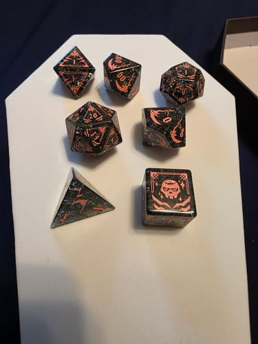 Reviewer's close-up of seven unique black and orange gaming dice.