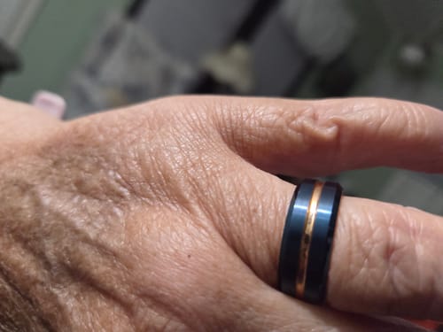 A close-up of a customer's hand wearing the Caelum ring, showing the blue band and rose gold central stripe.
