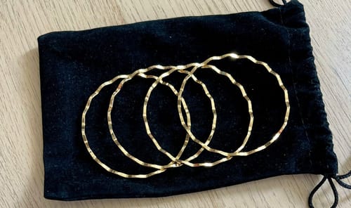 Customer's four wavy gold McAbee Rings resting on a black velvet pouch.