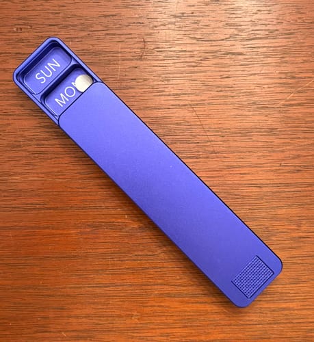 Reviewer showing the sliding cover of their purple Weekly Case, stopped at the Monday compartment.