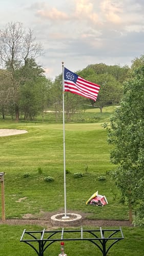 Reviewer's Betsy Ross Flag waving on a flagpole in a large, grassy yard.