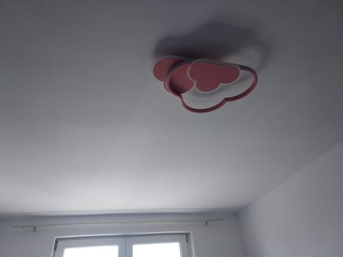 Clientul arată lustra LED NORISOR roz, în formă de nor, montată pe tavanul unui dormitor.