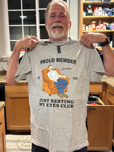 Customer holding up his personalized grey 'Proud Member Of Just Resting My Eyes Club' shirt.
