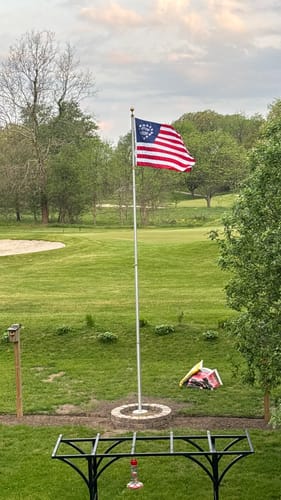 Reviewer's Betsy Ross Flag waving on a flagpole in a large, grassy yard.