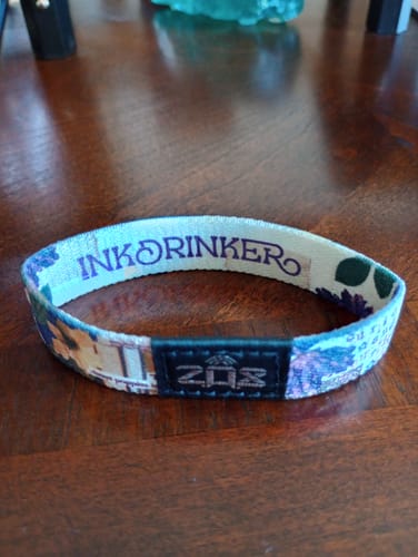 Customer's Inkdrinker Bracelet resting on a wooden table, with the product name visible on the inner band.