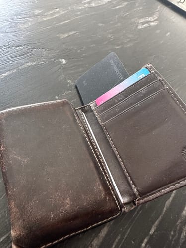 A reviewer's SPOTMINDERS Tracking Card shown fitting easily into a credit card slot in a dark brown leather wallet.