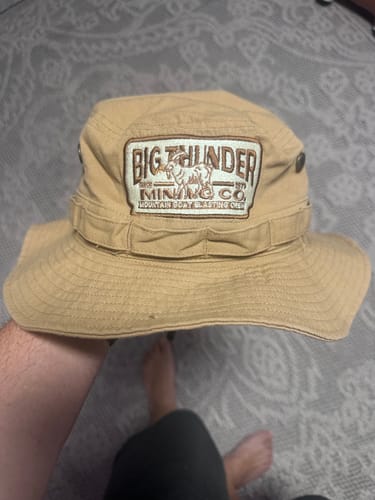Customer's tan bucket hat with a detailed custom embroidered patch on the front.